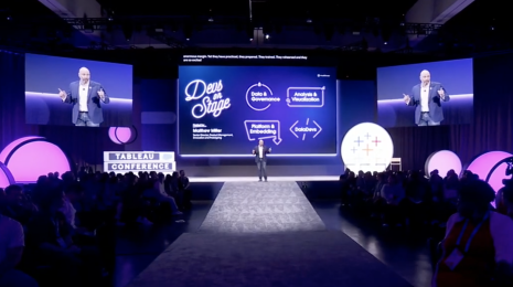 Light-skinned man presenting at Tableau Conference with purple screen with white text reading "Devs on Stage"